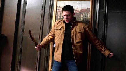 Abaddon pins Dean to the wall.